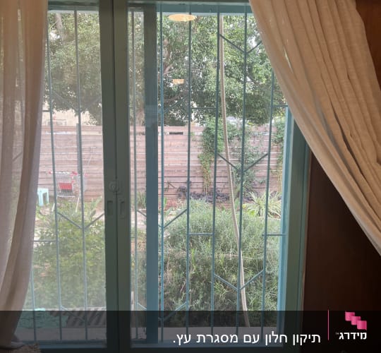 חלון זכוכית עם סורגים ווילונות לבנים